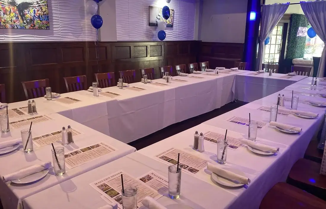 The first floor event space at Midtown Social set for a school dinner — long banquet tables in white linen, printed menus and balloons.