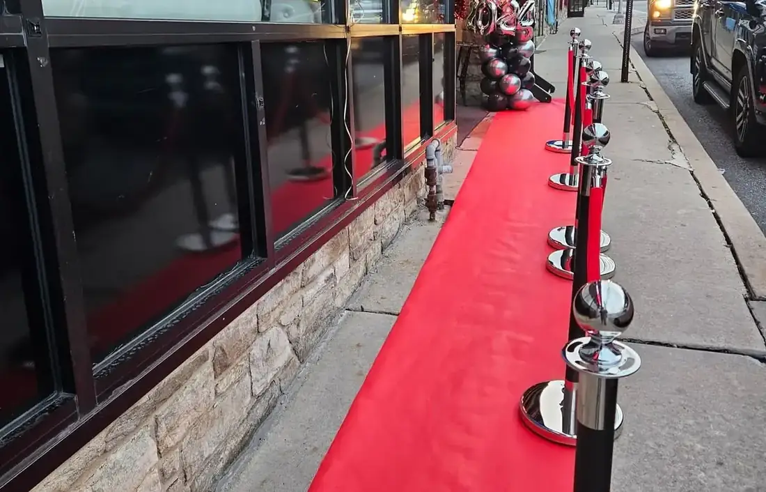 The Midtown Social frontage on Lancaster Avenue in Berwyn, with a red carpet and stanchions along the sidewalk.